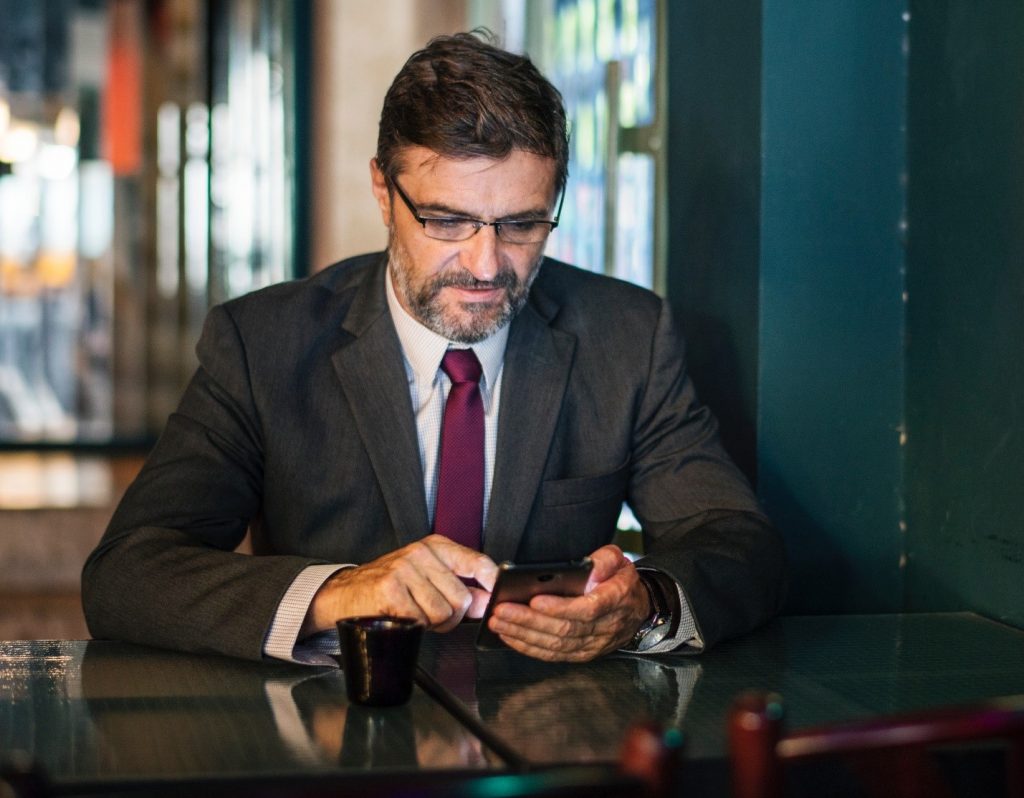 Man in suit searching his phone for advice for finding true love.