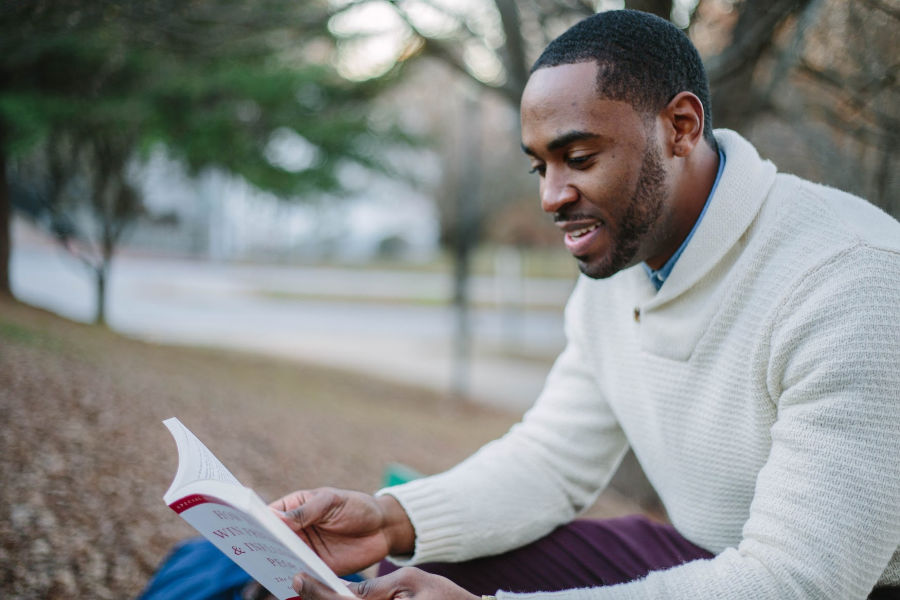 Shy man sitting outside and reading about dating advice for shy guys.
