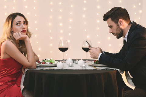 Couple at dinner who need relationship advice because they're ignoring each other.