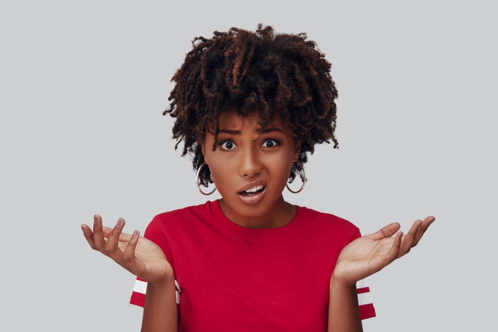 Woman with a frustrated expression holding her hands up and shrugging her shoulders.