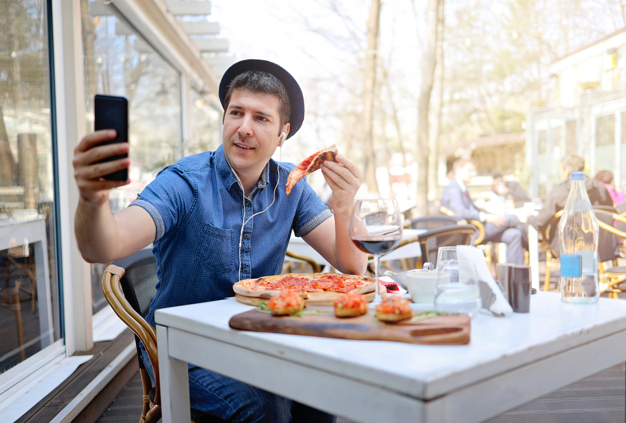 Man eating a pizza alone and taking a selfie.