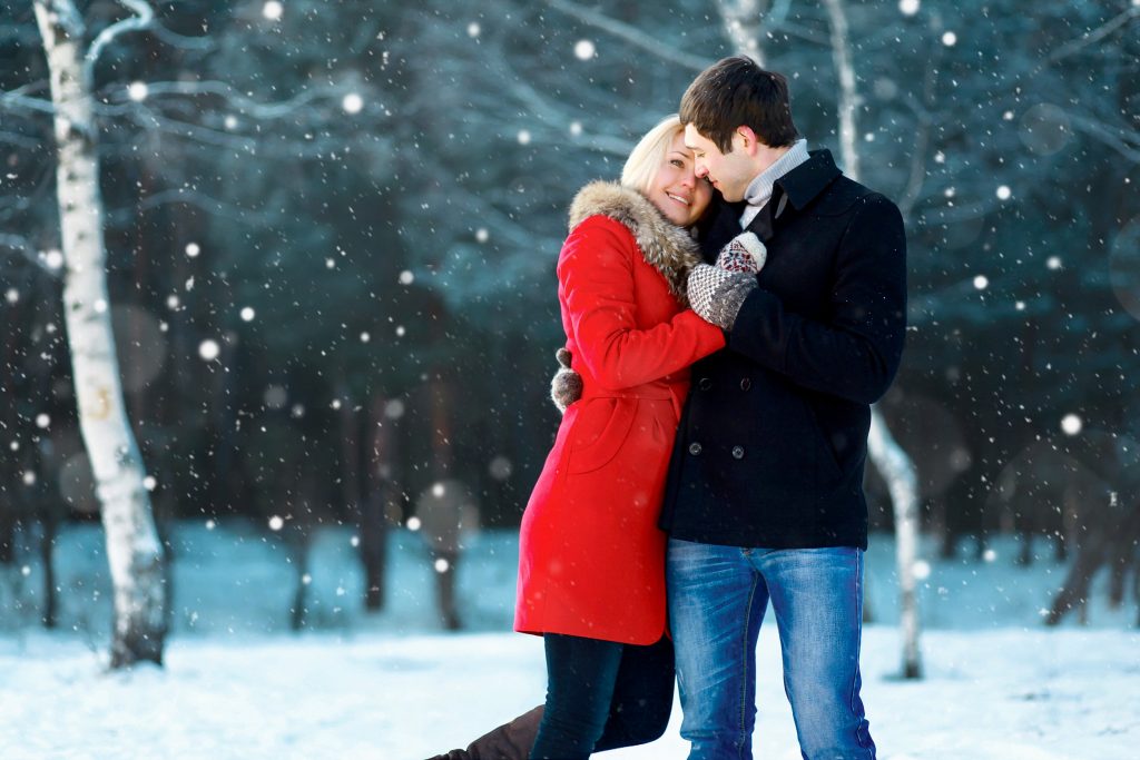 Man and woman sharing a loving embrace during a snow shower