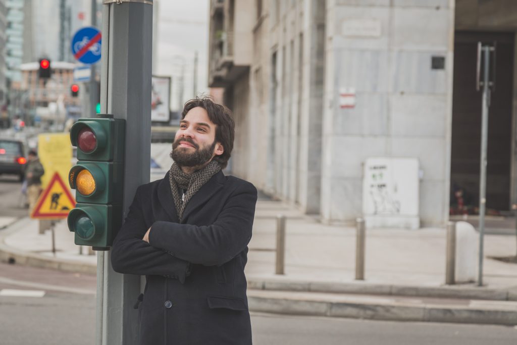 Man leaning on a street light post.