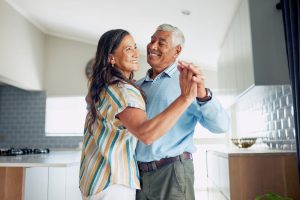 A happy couple dancing in their kitchen because they learned the relationship skill of asking for what you want.