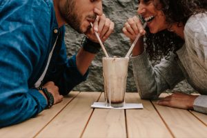 A man and a woman happily sharing a milkshake as they learnt of ind true love.