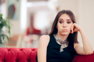 Frustrated woman sitting on a couch wondering why true love is so hard to find.