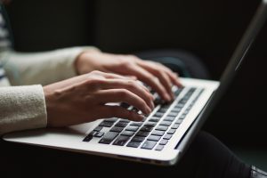 Woman using her laptop to create her profile using online dating tips for profile writing.
