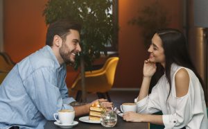Single man and single woman over 35 sitting with coffee and dessert enjoying their date.