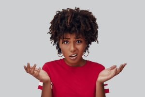 Woman with a frustrated expression holding her hands up and shrugging her shoulders.