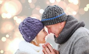 Couple staring happily into each other's eyes while snow falls around them.