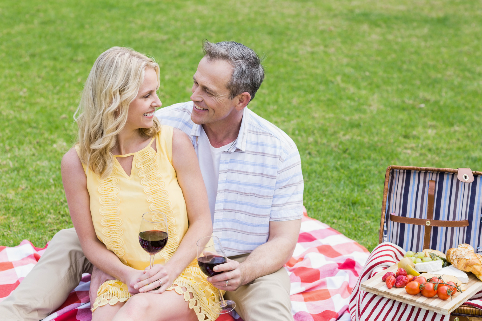 Man and woman cuddling while sharing a summer picnic.