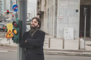 Man leaning on a street light post.