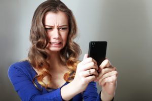 Woman looking at her phone in disgust.