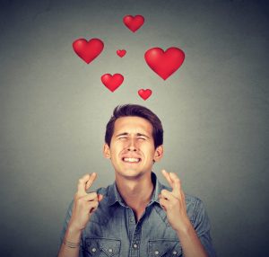 Man dreaming of his true love and crossing his fingers.