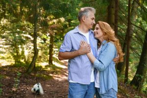 A happy couple embracing on a path in the woods.