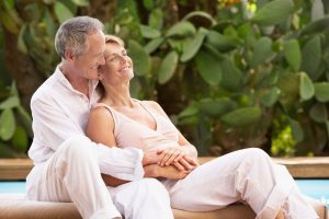 Mature couple who finally found long-lasting love blissfully holding each other outside by the pool.