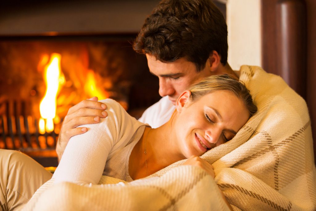 Couple who has built trust in their relationship cuddling by the fire.