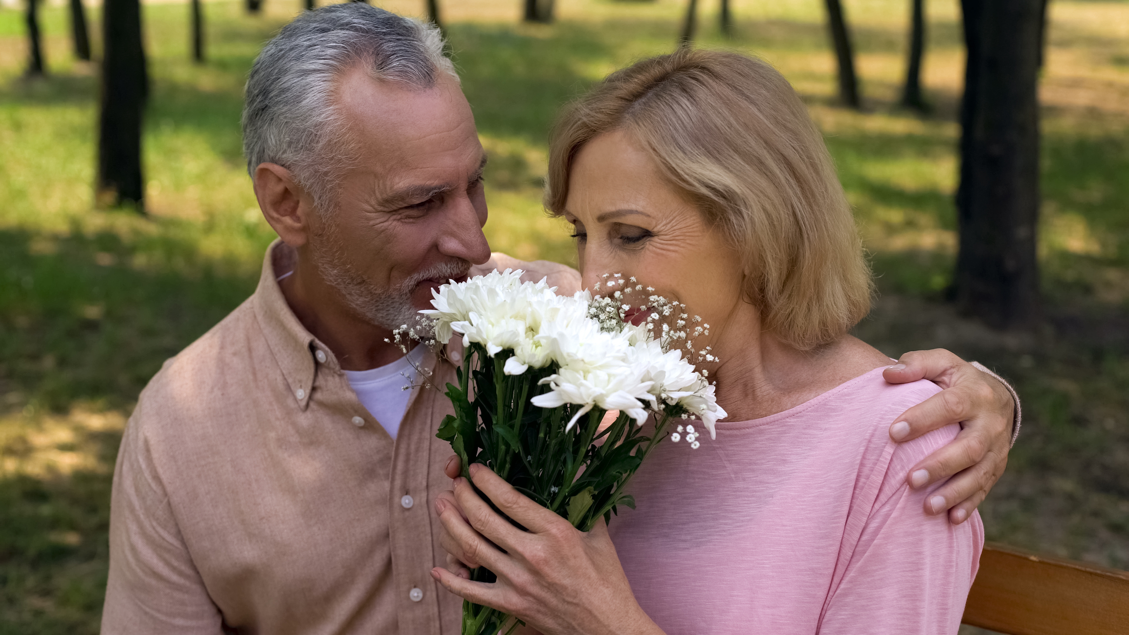 Man with his arm around is date after giving her flowers as a gesture of his true love.