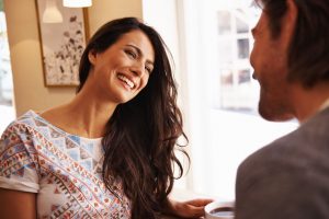 A happy couple on a first date in a coffee shop, discussing dating expectations.