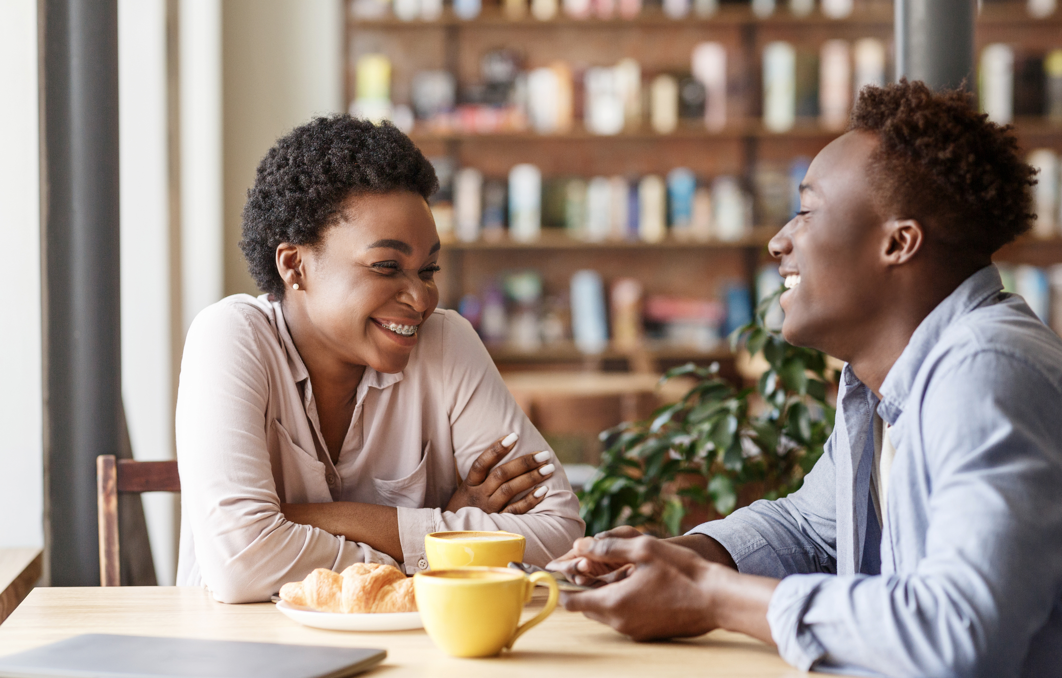 A happy couple on a first date in a coffee shop, discussing dating expectations.