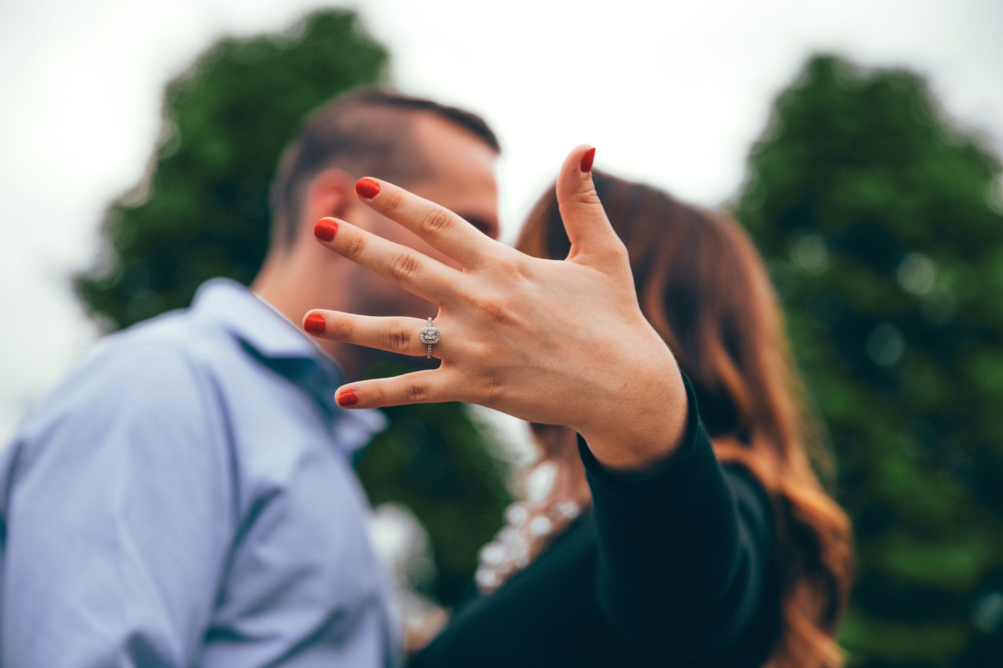 A kissing couple, who understood that dating to marry is different than just dating, showing off the engagement ring on her finger!