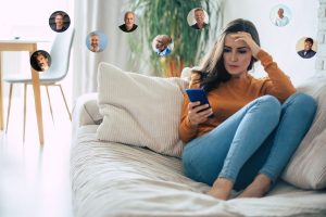 Woman on her couch looking worried as she is overwhelmed by too many online dating matches and reconsidering her online dating strategies.