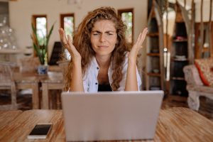 A woman who is frustrated with dating shakes her hands at her computer.