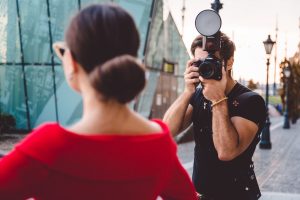 Online dating photographer taking better profile pictures of a woman in a red dress.